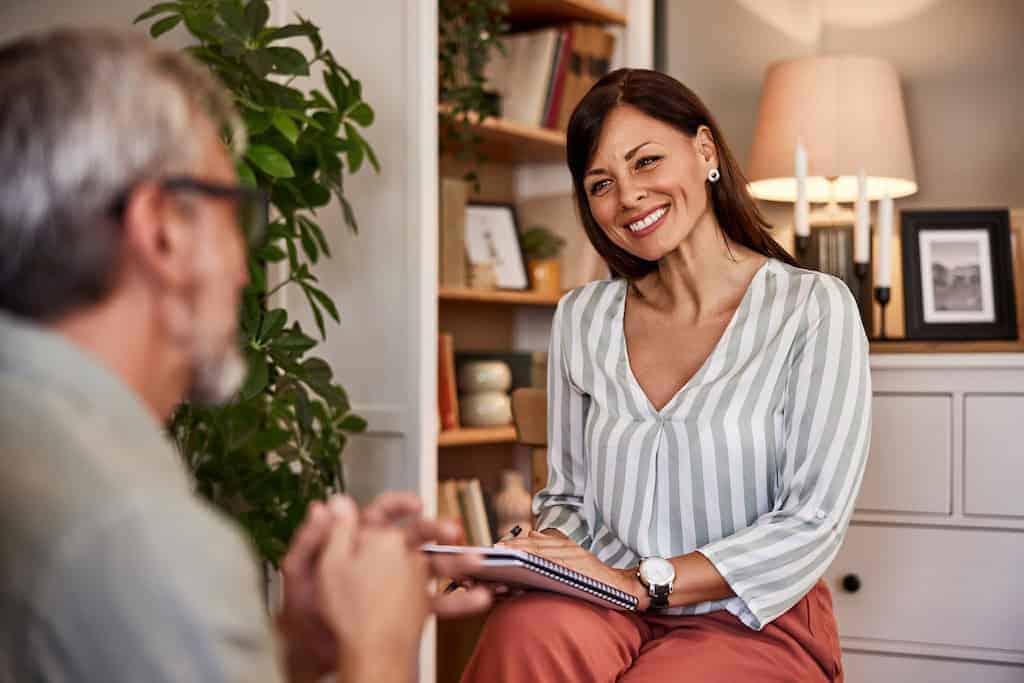 Professional recovery coach talking with male client in comforting office setting